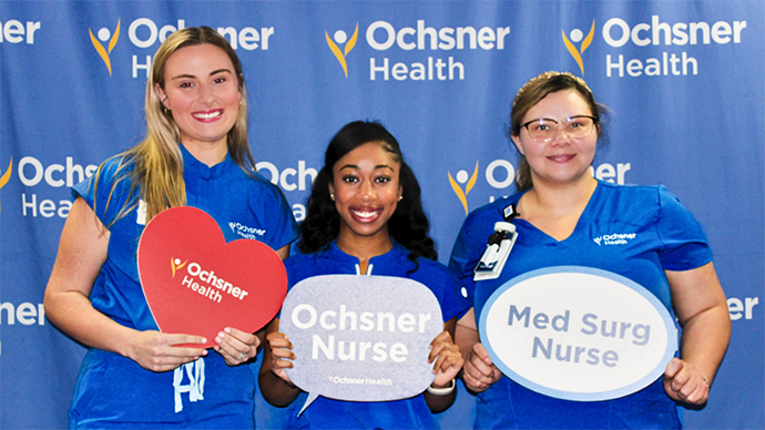 Ochsner Lafayette General Foundation: An image of three female nurses.  Each are holding a sign in their hands.  One is a heart with an Ochsner Health logo in the shape of a heart.  The next is a quote shape with Ochsner Nurse as text on it.  The third is an oval with the text Med Surg Nurse on it.